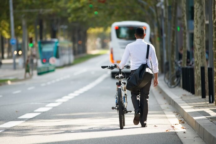 Businessman Walking with Bike in Street After Work
